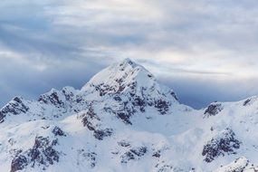 Landscape with the beautiful mountain peak in snow under cloudy sky