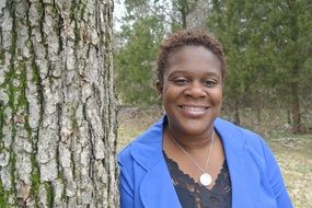 portrait of African American woman stands near the tree