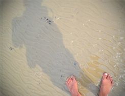 feet and shadow on sand beach