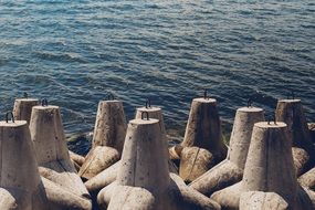 rows of concrete wave breakers on beach at water