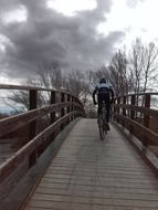 a man rides a bicycle on a bridge