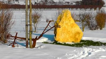 iron plow and yellow kament on a winter field in the countryside