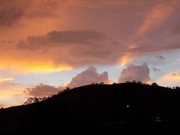 rays of light and pink clouds on top of a hill