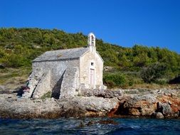 Chapel on the beach with colorful rocks and plants in Hvar, Croatia