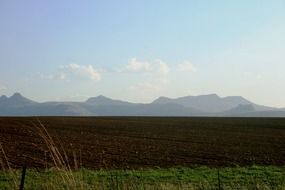 Beautiful landscape with the tilled land, grass and mountains