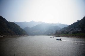 boat on wide calm river at foggy mountains, china, xinanjiang