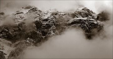 black-white image of the snowy mountains in the clouds in Switzerland