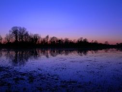 Landscape of flooding meadow under colorful sunset