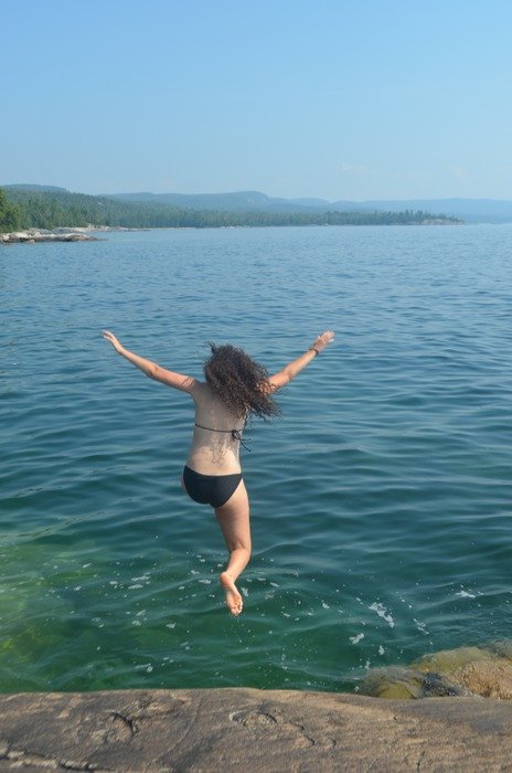 girl in a swimsuit jumps into the water from a cliff