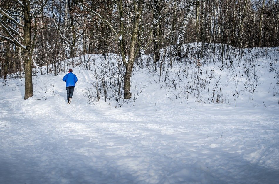 man runs through the snow in the forest