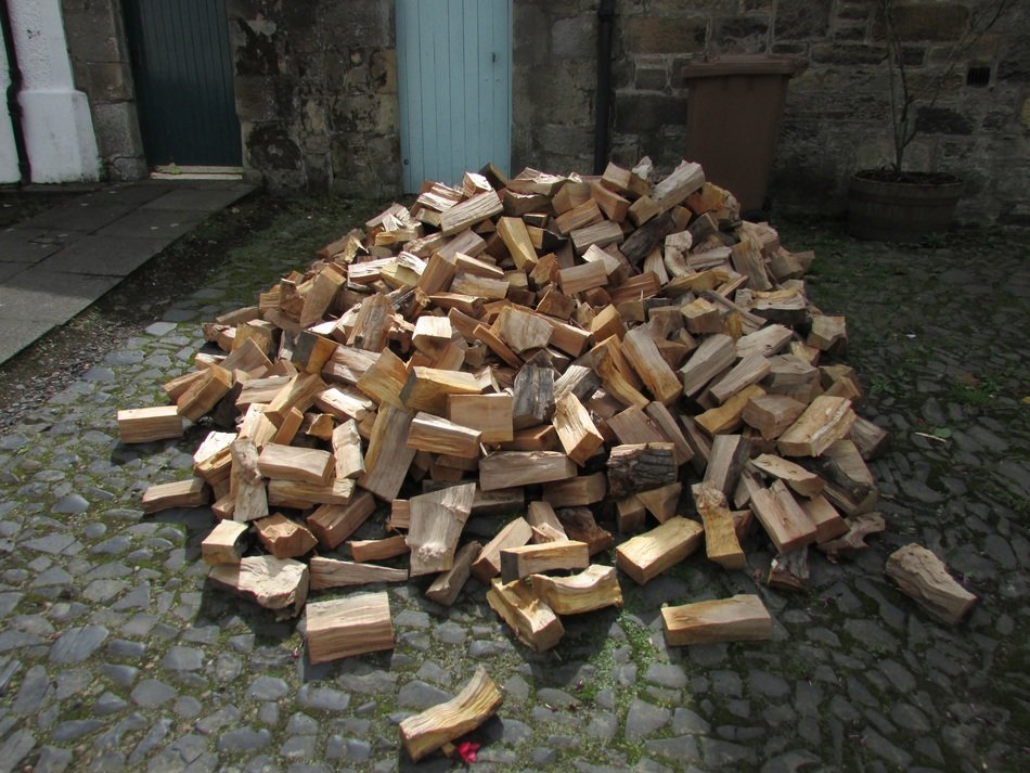 chopped firewood lies by the barn