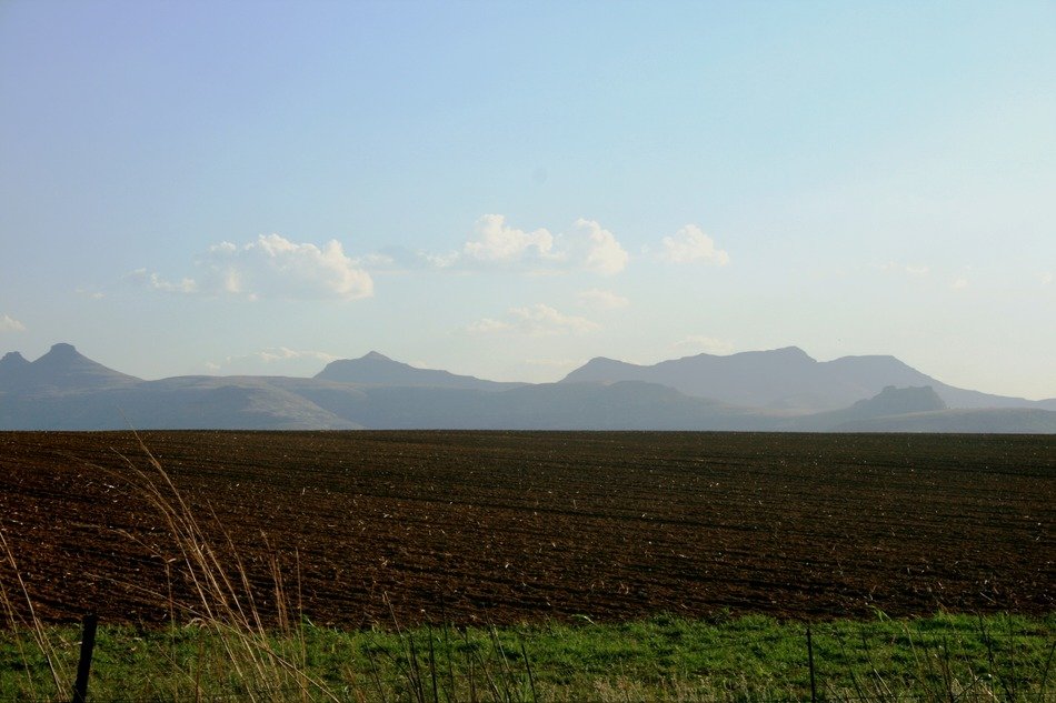 Beautiful landscape with the tilled land, grass and mountains