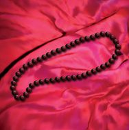 Black pearls a necklace on red fabric Vector