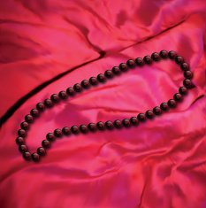 Black pearls a necklace on red fabric Vector
