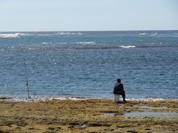 fisherman sits on beach at sea