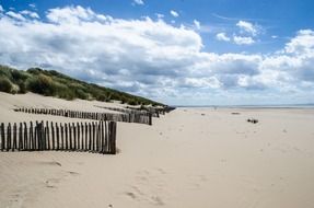 Fences on the beautiful sandy beach under blue sky with white clouds