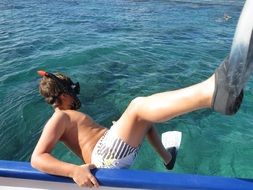 man jumps from a boat into the water