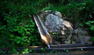photo of water pours down the gutter in the forest