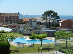 Blue swimming pool among the buildings and plants on landscape
