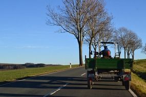 green tractor is driving on the road