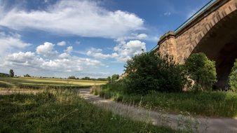 landscape of fluffy clouds and bridge in fields