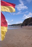 Red and yellow flags on a sand beach