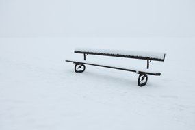 snow on a bench in a winter park in December