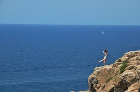 girl is doing yoga on the top of the rock on a sunny day