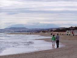 young couple walks along the evening sea