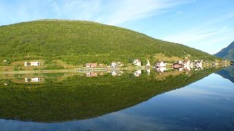 picturesque landscapes of norway are reflected in the water on a clear sunny day