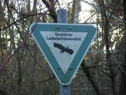 protected landscape, triangular sign on pole at forest