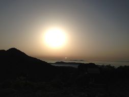 the sun behind the mountain at dusk