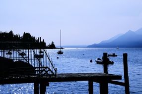 pier and boats at coast in blue dusk seascape, italy, garda