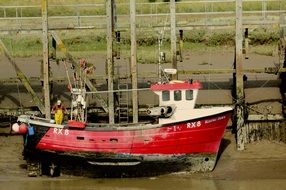 man on red fishing boat on sand