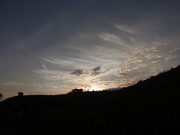 clouds and sun at sunrise above the hills