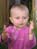 little girl with a green twig of grass