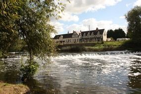 old pub on river bank at dam, uk, england