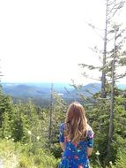 Blonde girl in a blue dress on a background of a beautiful mountain forest