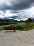 landscape of thunderclouds over a bench on the shore