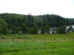landscape of a green meadow on a background of picturesque hills and lake