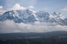 panorama of snowy mountains in the fog on a sunny day