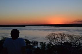 man watches the sunset over the river