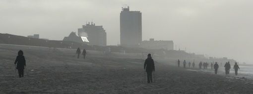 people walking on beach at sea on wintry foggy weather, germany, sylt