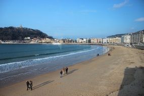 people are walking on the beach on a sunny day