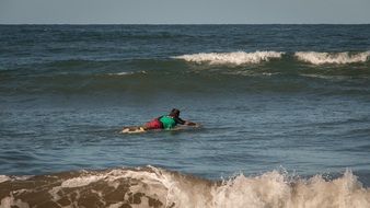 man floats on a rocky beach