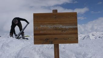 man on a snowy mountain near a wooden sign