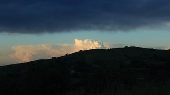 white clouds behind the mountain at dusk