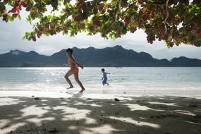 A man with a child plays on the beach