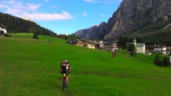 person cycling away to village