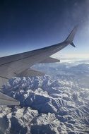 wing of the plane over the tops of the mountains